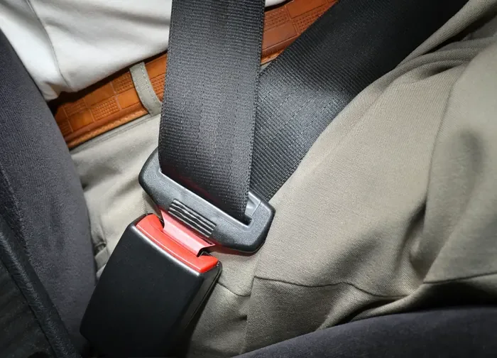 Seat belt fastened across an occupant showing the lap section and buckle engagement