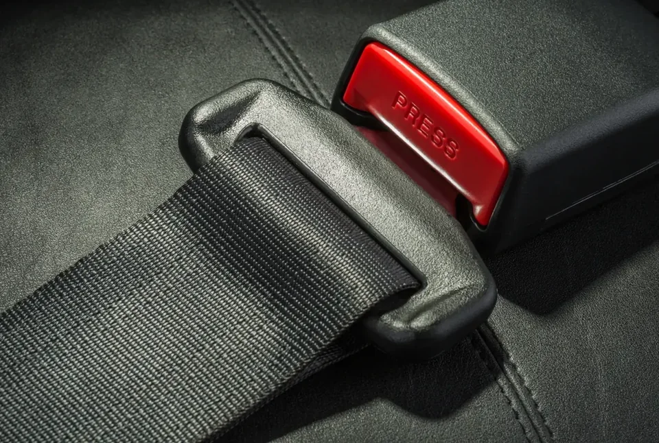 Retractable seat belt webbing engaged in a buckle with a red release button