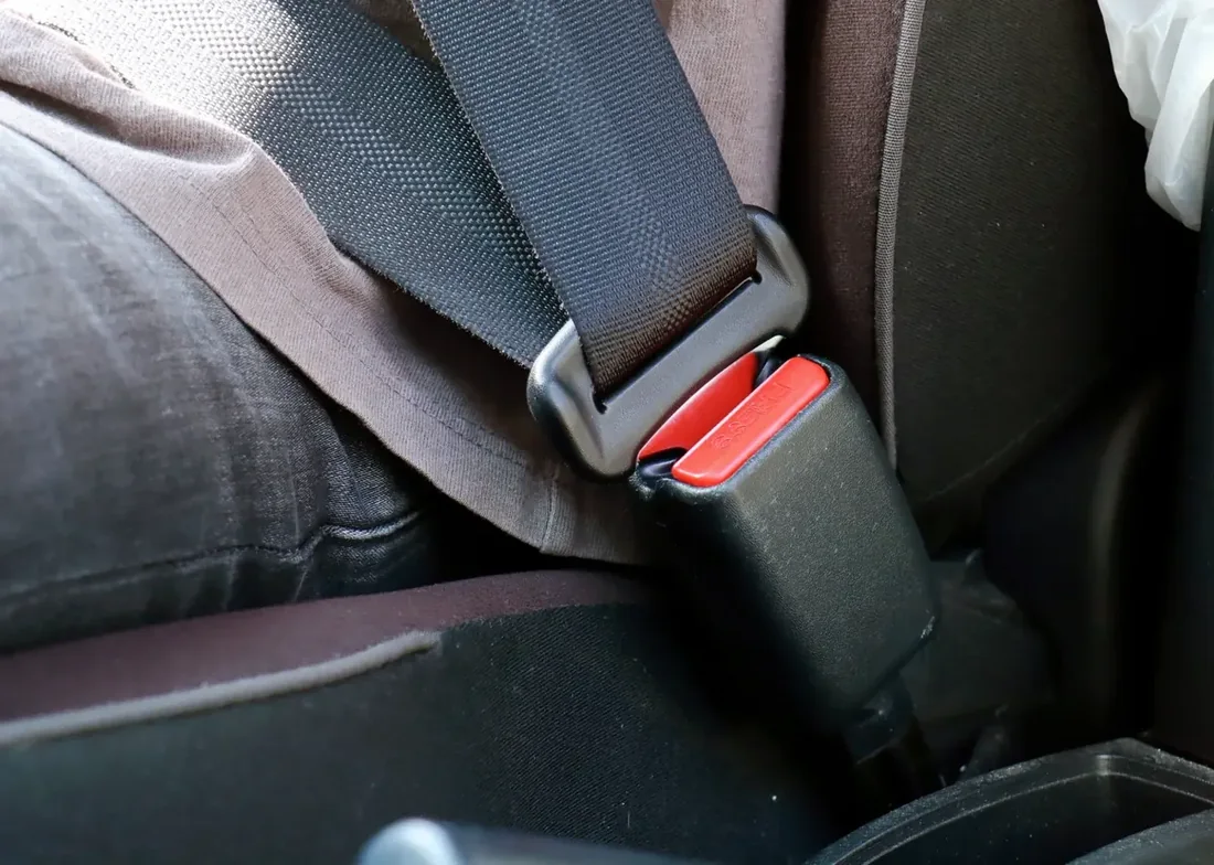 Seat belt fastened across an occupant with the buckle and red release button clearly visible
