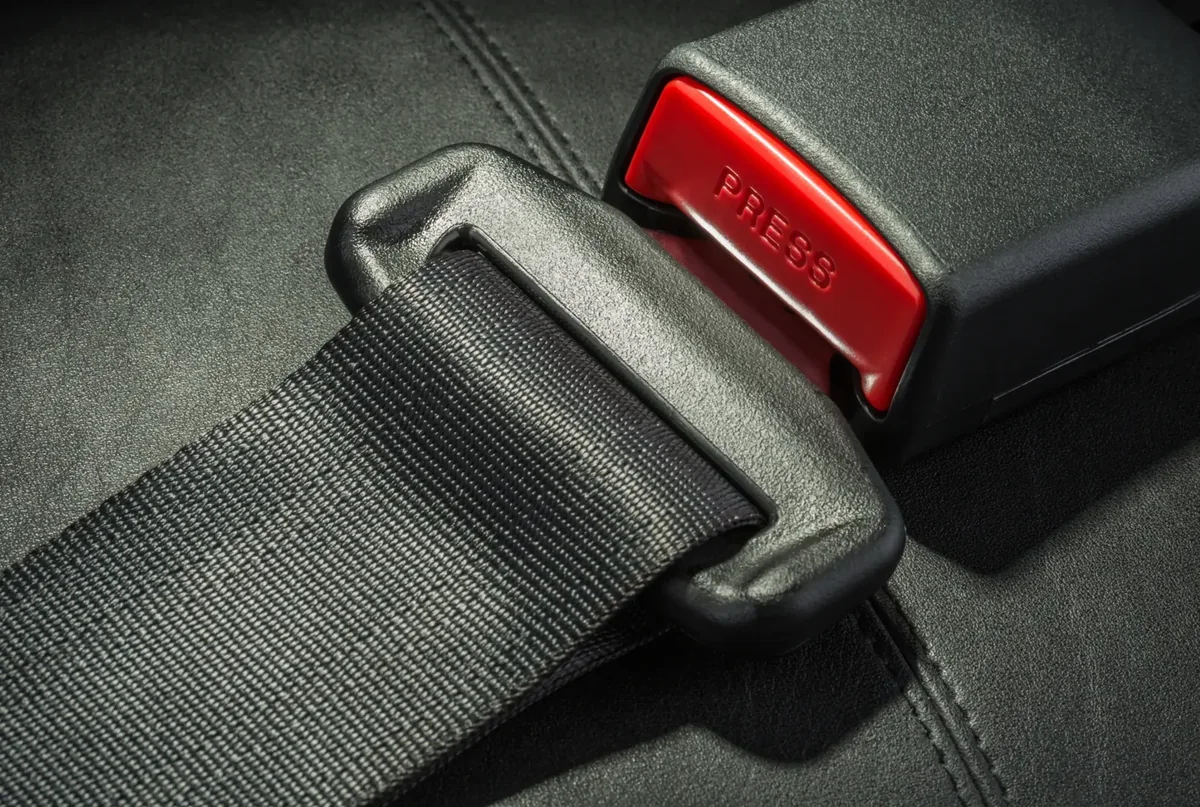 Close view of a seat belt assembly showing webbing, latch plate and buckle housing