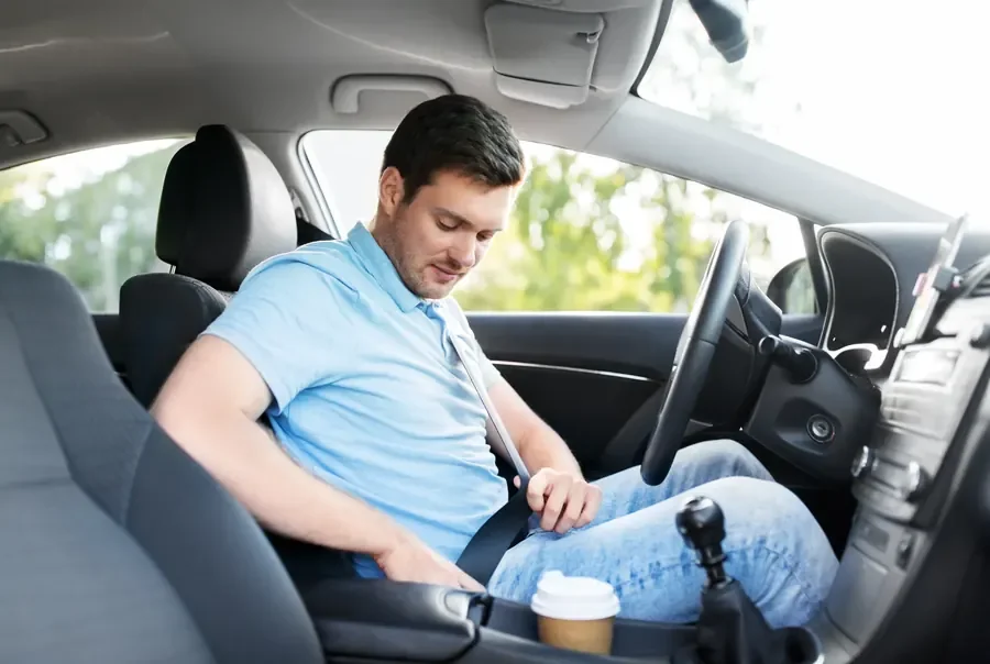 Occupant seated in a passenger car with a three-point seat belt fastened across chest and lap